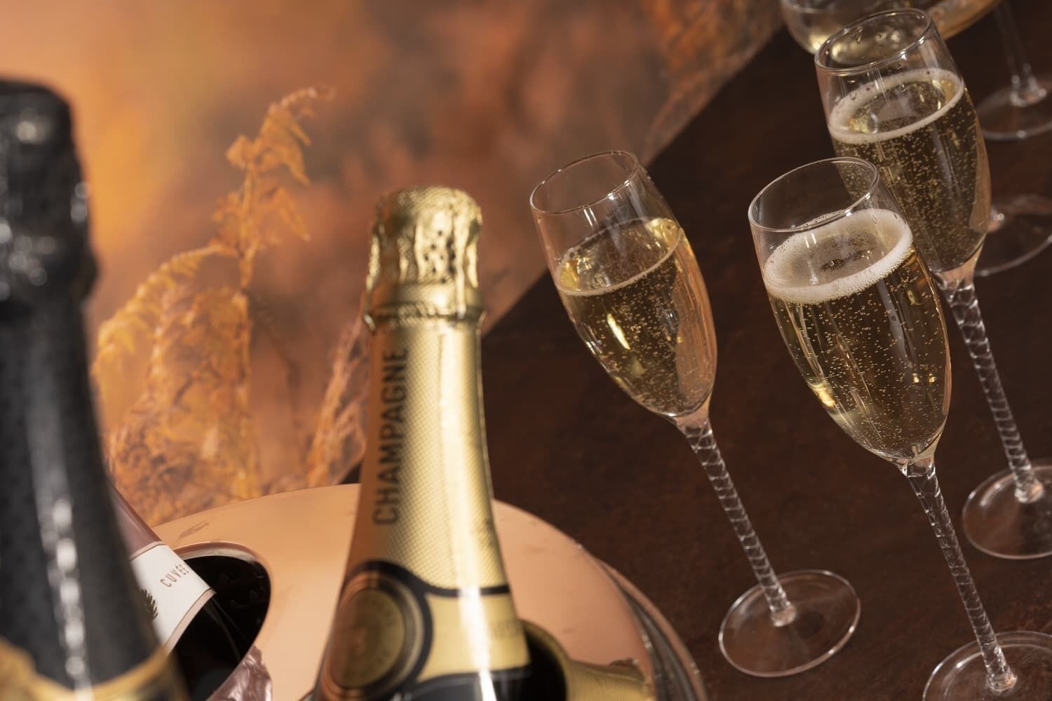 Eine Champagnerflasche und drei mit Champagner gefüllte Gläser.
