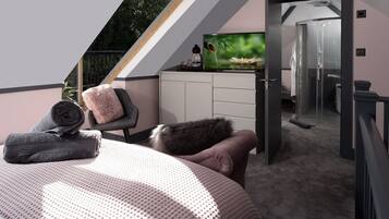 A modern bedroom with a bed, a chair, a desk, and a shower area.