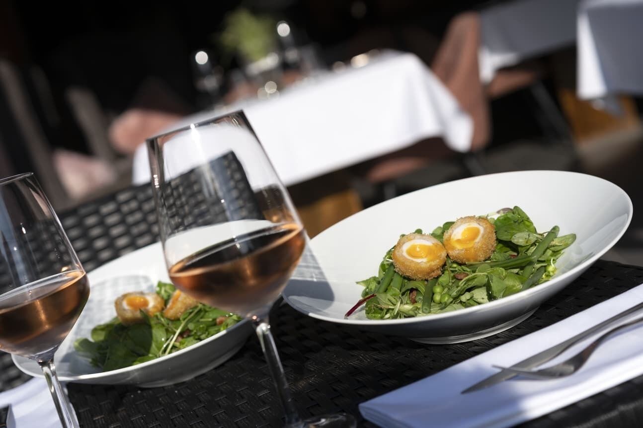 Una mesa de comedor con un plato de comida y dos copas de vino.