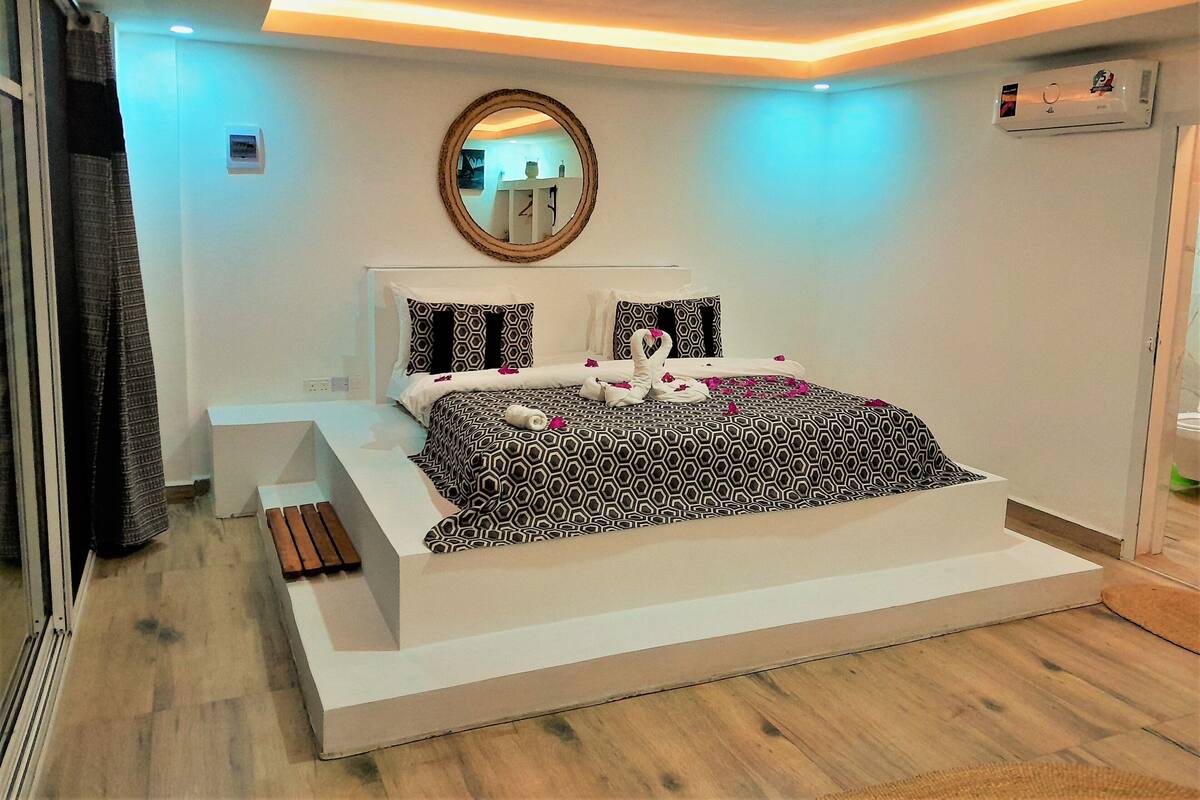 Un dormitorio moderno con una cama grande, un espejo y un banco empotrado.