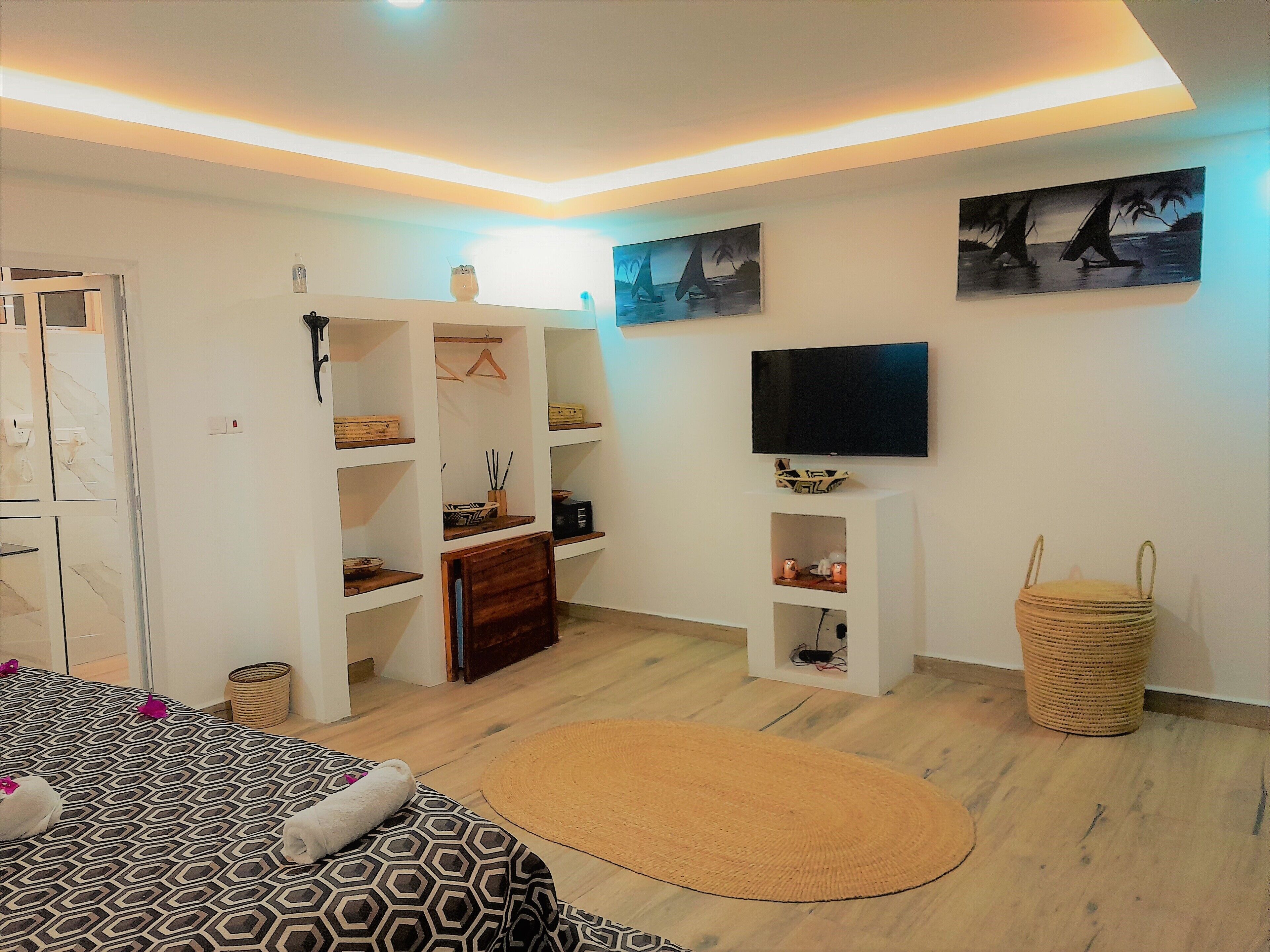 Un dormitorio moderno con cama, televisor y armario.