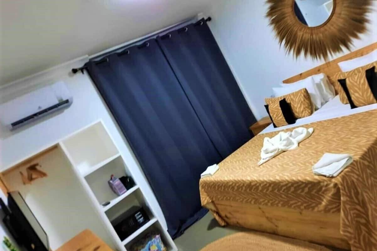 Una habitación de hotel con cama, armario, espejo y cortina.
