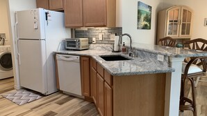 A kitchen with wooden cabinets, a built-in microwave, a sink, and a dishwasher. - Beautiful 2/2 Villa w/4 Seater Gas Golf Cart, BBQ Grill, and WiFi!! (The Villages)
