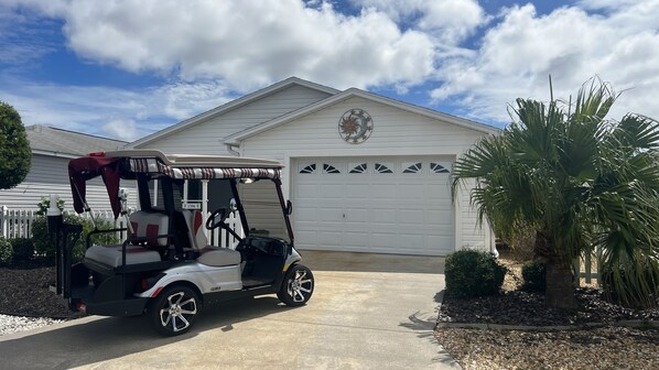 Ein Golfmobil steht vor einem Haus mit Garage.