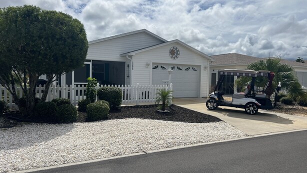 A residential house with a white picket fence, a driveway, and a golf cart parked in front. - Beautiful 2/2 Villa w/4 Seater Gas Golf Cart, BBQ Grill, and WiFi!! (The Villages)