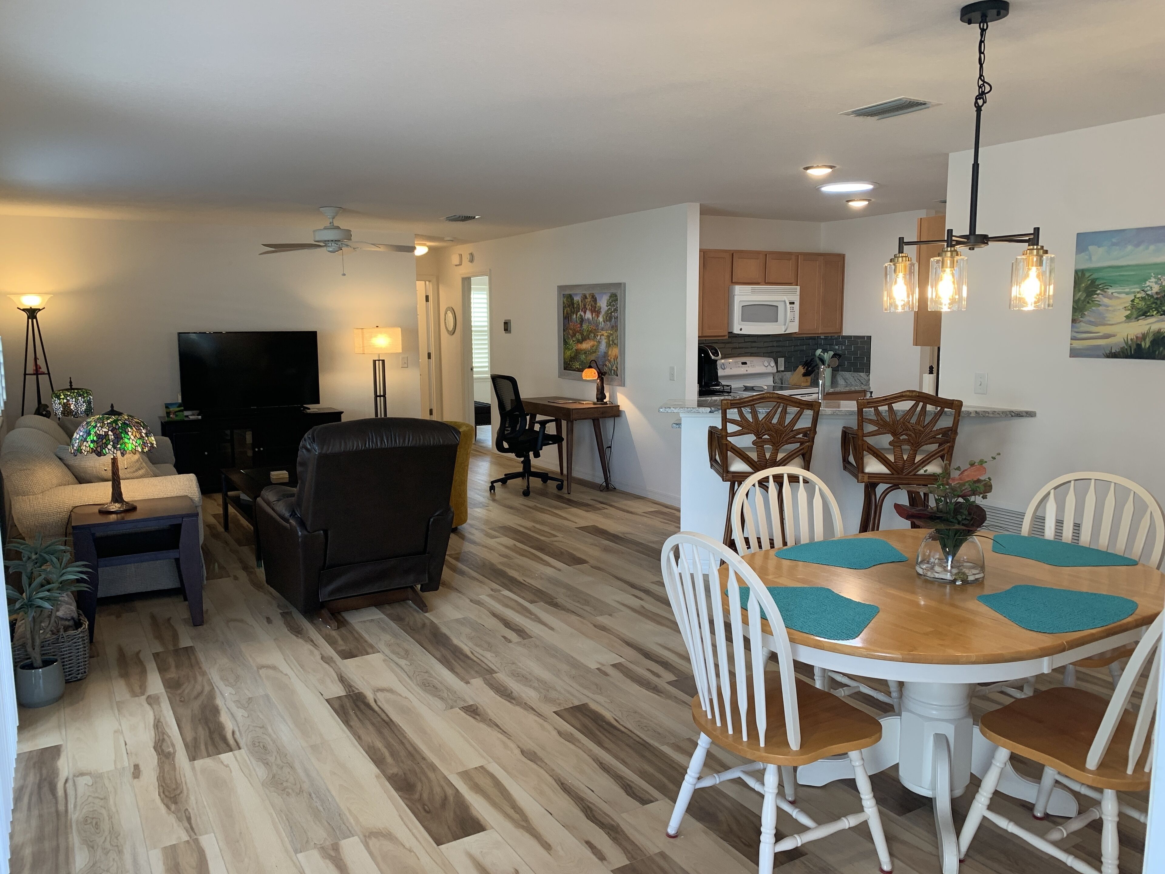 Uma sala de estar moderna com um sofá, TV e um espaço de jantar com mesa e cadeiras.