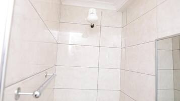 A tiled shower area with a handrail and a ceiling-mounted light fixture.