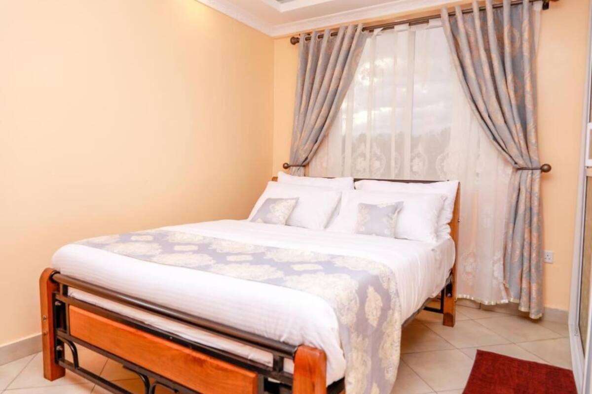 Un dormitorio con cama, cortinas y alfombra roja.
