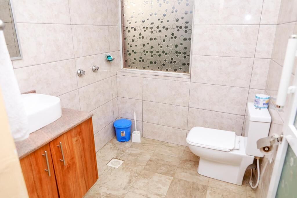 Et lille badeværelse med toilet, vask og brusebad.