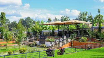 Hotel com design moderno, apresentando uma área externa coberta com escadas que levam a um edifício, cercado por vegetação exuberante e palmeiras.