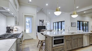 Een moderne keuken met een ruim kookeiland, roestvrijstalen apparatuur en hanglampen.