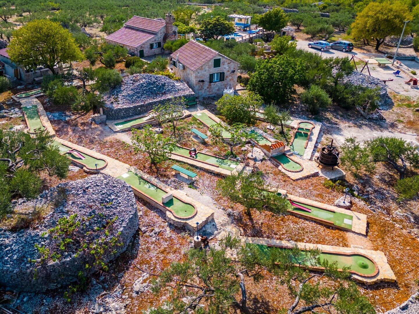 An aerial view of a property with multiple buildings, a golf course, and surrounding vegetation.