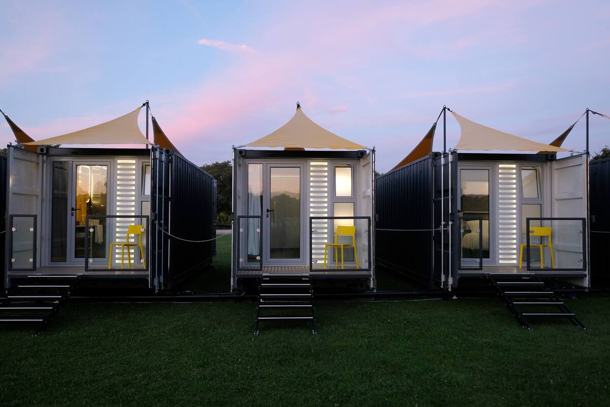 Three modular cabins with sliding doors, each featuring a small set of stairs leading to the entrance.
