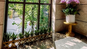 Un coin de pièce avec une grande fenêtre en arc de cercle, une orchidée en pot et une petite table.