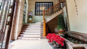 Un vaste hall d’entrée agrémenté d’un lustre, d’un escalier et d’une enseigne indiquant « Trang Thai, appartement de luxe ».