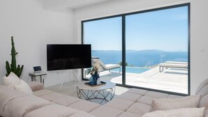 A modern living room with a large TV, a laptop, and a coffee table with a vase. - Villa Aristea with sea view, jacuzzi&infinity pool (Ripenda Kosi)