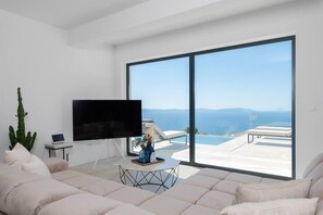 A modern living room with a large TV, a laptop, and a coffee table with a vase. - Villa Aristea with sea view, jacuzzi&infinity pool (Ripenda Kosi)