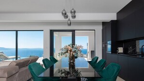 A modern dining area with a glass table, teal chairs, and a vase of flowers. - Villa Aristea with sea view, jacuzzi&infinity pool (Ripenda Kosi)