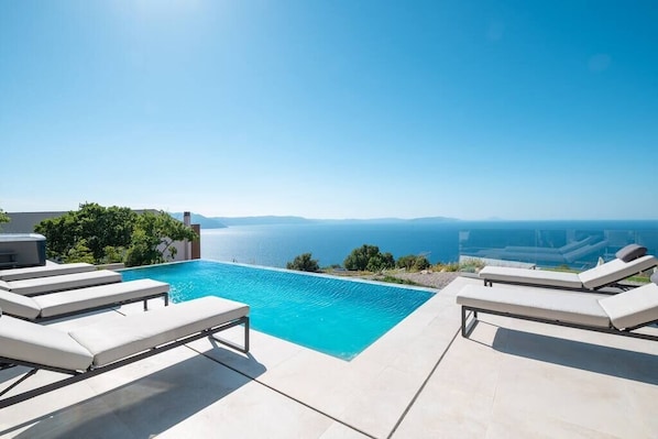 A poolside area with lounge chairs and a view of the sea.