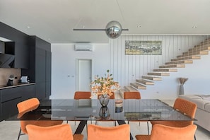 A modern kitchen with a glass dining table, orange chairs, and a staircase with wooden steps. - Villa Ultima with sea view, private pool&jacuzzi (Ripenda Kosi)