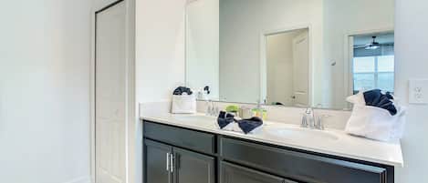 A modern bathroom with a double vanity, a large mirror, and a walk-in shower.
