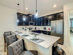 A modern kitchen with dark cabinets, stainless steel appliances, and a central island with seating.