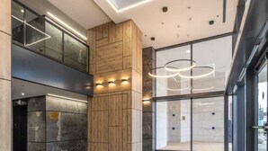 En modern entréhall med en väggpanel i trä, en glashiss och en rund lampa.