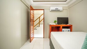A hotel room with a bed, a desk with a computer, a TV, and an air conditioner. - POUSADA MARIA DO LAMPIÃO  (Jijoca de Jericoacoara)