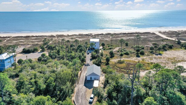 Une propriété située sur la côte, comprenant une maison principale et un bâtiment plus petit, le tout entouré d’une végétation luxuriante et offrant une vue dégagée sur l’océan.