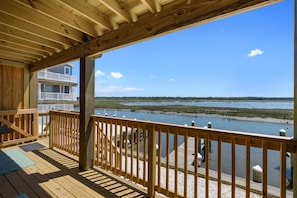 A wooden deck with a railing overlooking a body of water and a distant building.