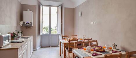A modern kitchen with a built-in microwave, a water heater, and a dining area with wooden chairs and a table set for breakfast.