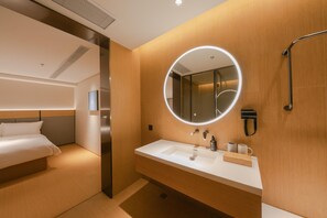 Une chambre d’hôtel avec un lit, une salle de bain comprenant un lavabo, un miroir et une douche.