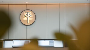 Un comptoir d’accueil avec une pancarte affichant des caractères chinois, deux imprimantes et un mur orné de lignes verticales.