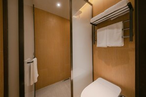 Ein modernes Badezimmer mit Duschabtrennung aus Glas, einer weißen Toilette und einem Handtuchhalter mit mehreren Handtüchern.