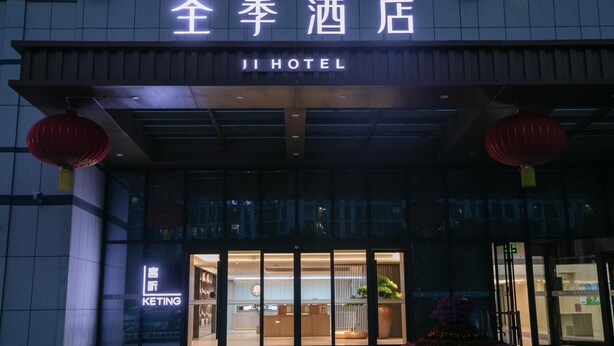 L’extérieur d’un hôtel, avec une enseigne indiquant « JI HOTEL » et une plus petite enseigne en dessous portant l’inscription « KETING ».