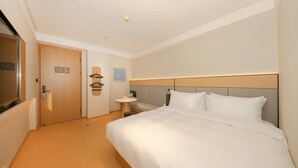 Habitación de hotel con una cama grande, una mesita de noche, una pequeña mesa redonda y un perchero para toallas en la pared.