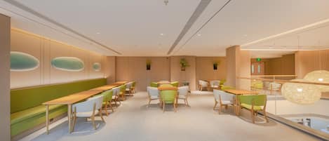 A modern interior with a long bench seating area, tables, and chairs.