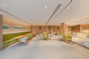 A modern interior with a long bench seating area, tables, and chairs. - Ji Hotel (Beijing)
