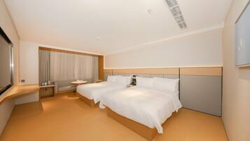 A hotel room with a large bed, bedside tables, a desk, and a TV.