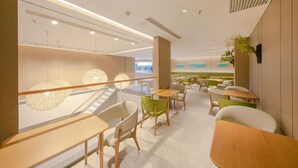 A modern interior with wooden tables and chairs, a staircase, and a view of the outside. - Ji Hotel (Beijing)
