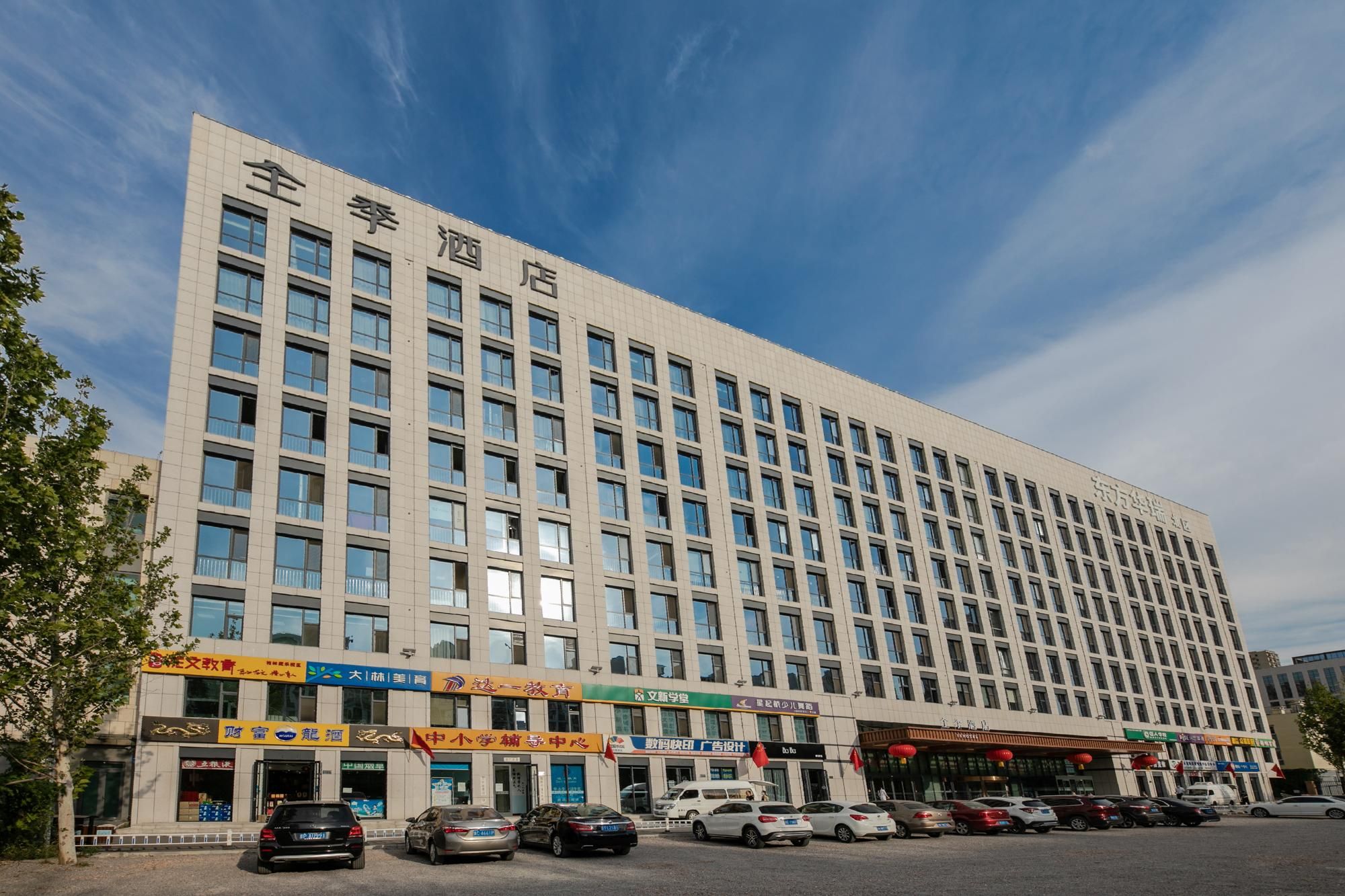 Un edificio alberghiero a più piani con una fila di negozi al piano terra.