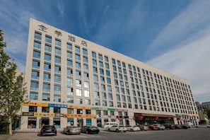 Un edificio alberghiero a più piani con una fila di negozi al piano terra.