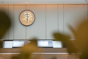 A reception desk with a wall-mounted sign displaying Chinese characters, two digital check-in kiosks, and a marble countertop. - Ji Hotel (Beijing)