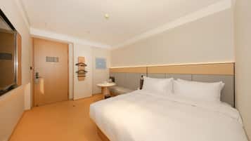 Habitación de hotel con una cama grande, una mesita de noche, una pequeña mesa redonda, un espejo y una puerta.
