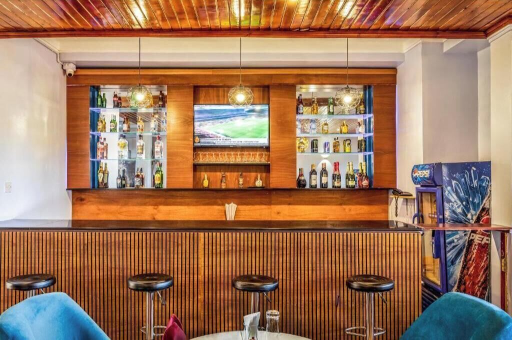 A bar area with wooden paneling, a television, and shelves of bottles.