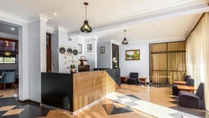 Een hotel lobby met een receptiebalie, een zithoek en een eetruimte.