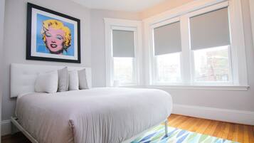 Un dormitorio con cama, un cuadro en la pared y una ventana con persianas.