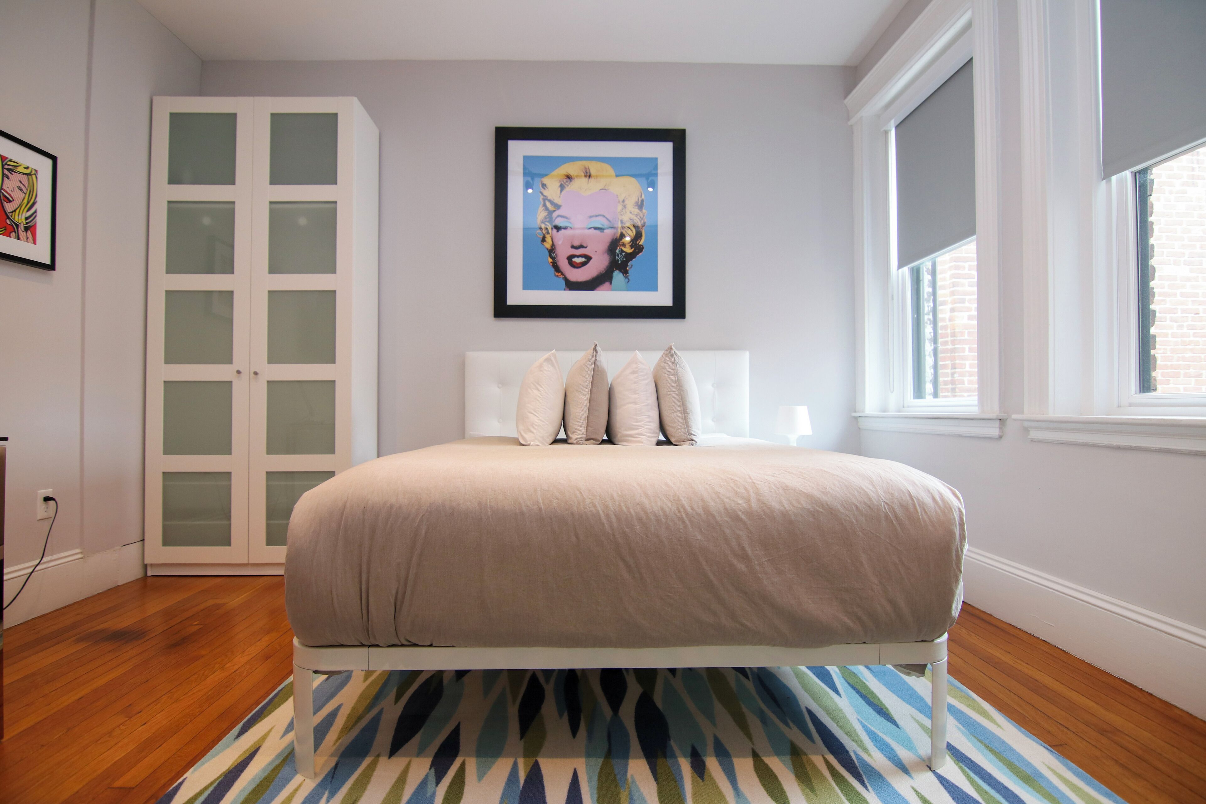 Une chambre à coucher avec un lit, une fenêtre, une porte et un tableau encadré au mur.