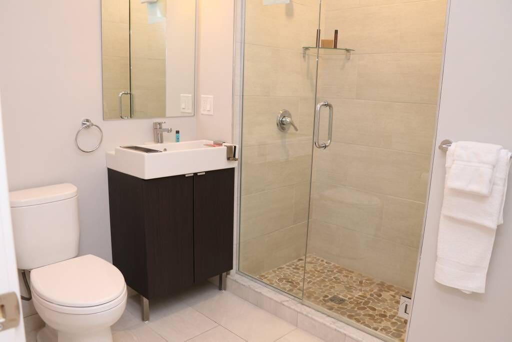 A modern bathroom with a toilet, sink, and glass-enclosed shower.