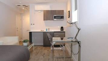 A compact living space with a kitchenette, a dining area, and a bed.